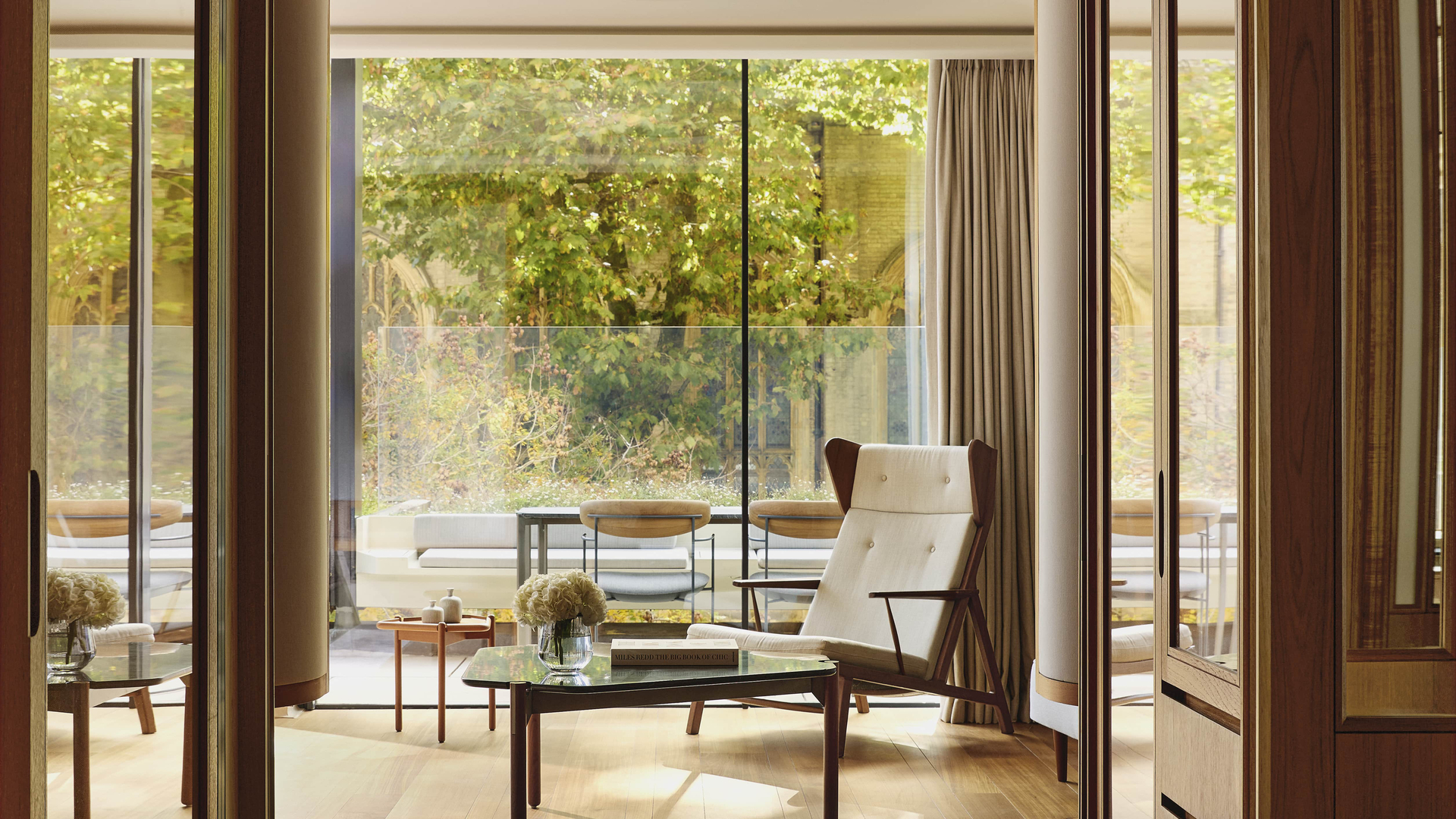 Elegant suite interior with mid-century furnishings and views of a private terrace garden.