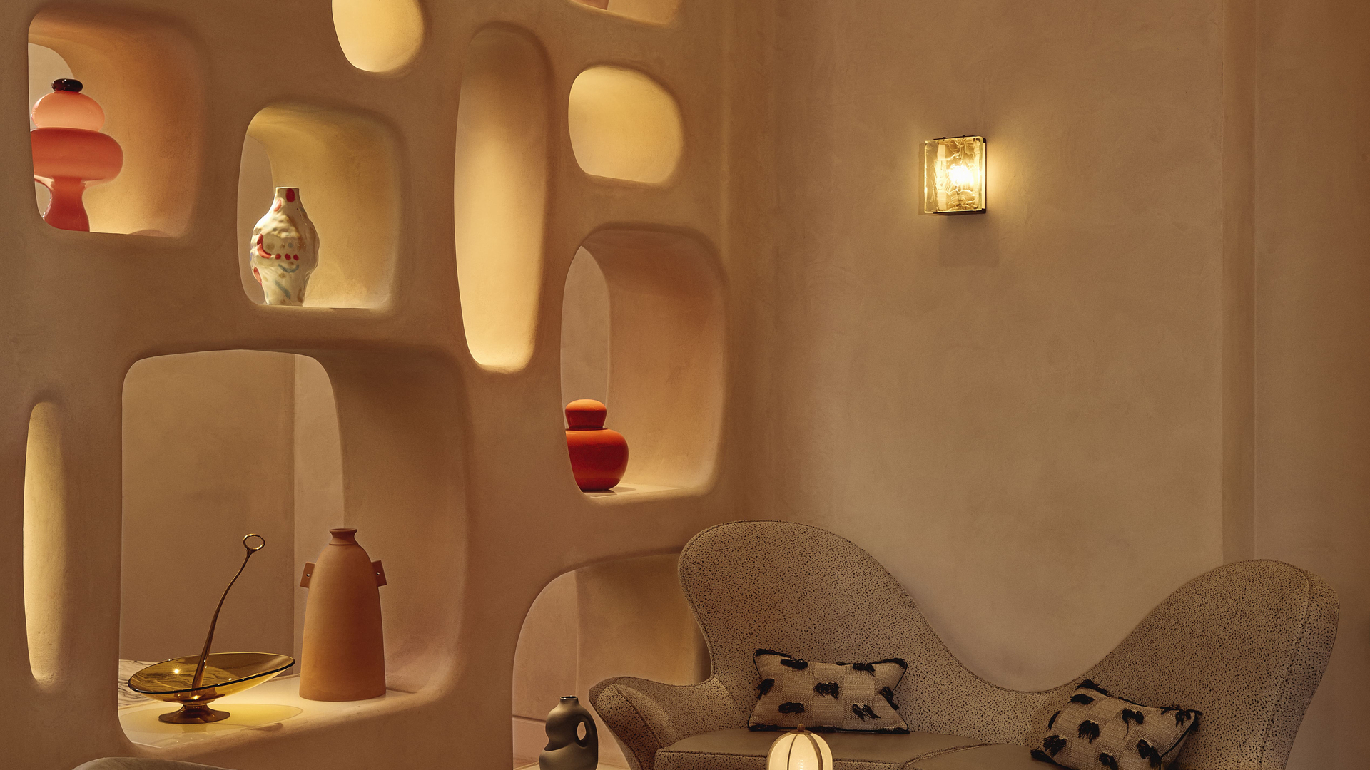 Curved lounge seating with sculptural shelving and warm lighting in a contemporary, artful interior.