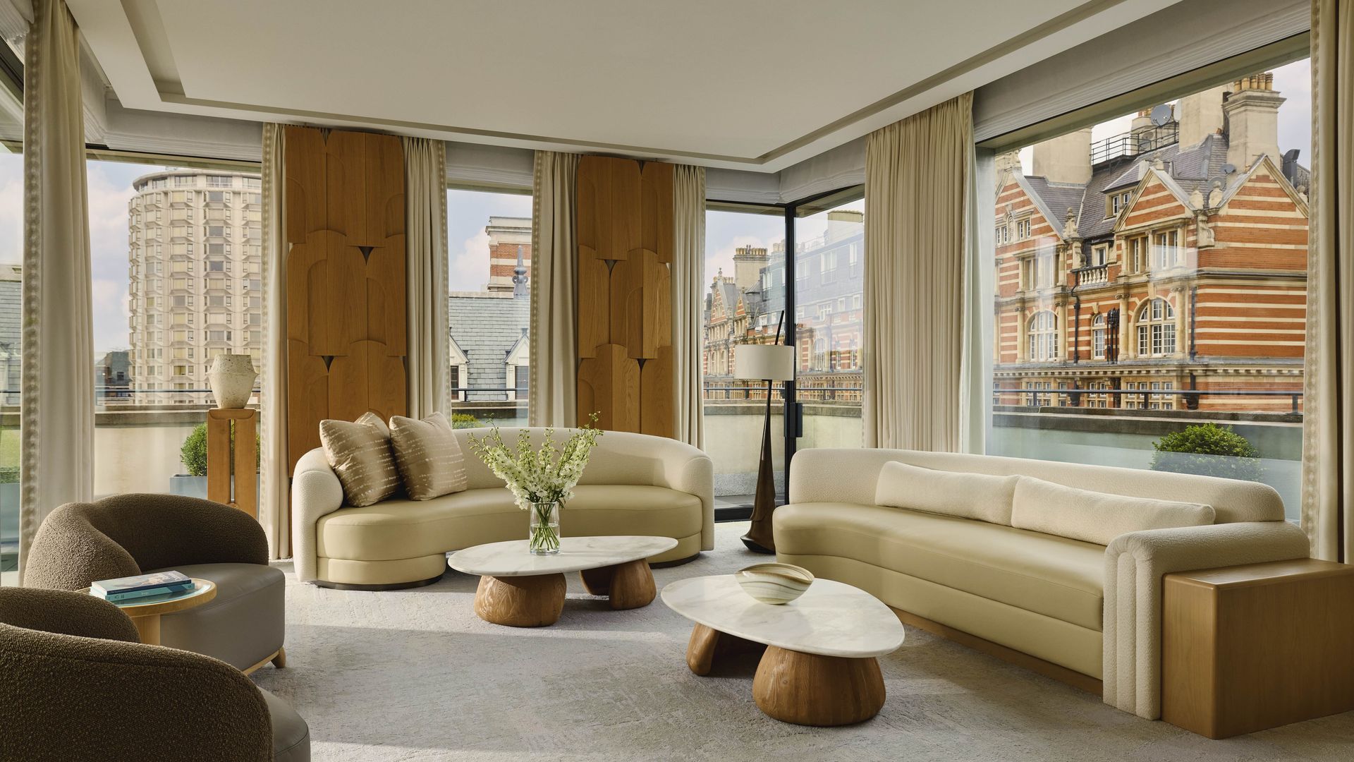 Spacious living room with modern furnishings and panoramic city views through floor-to-ceiling windows.