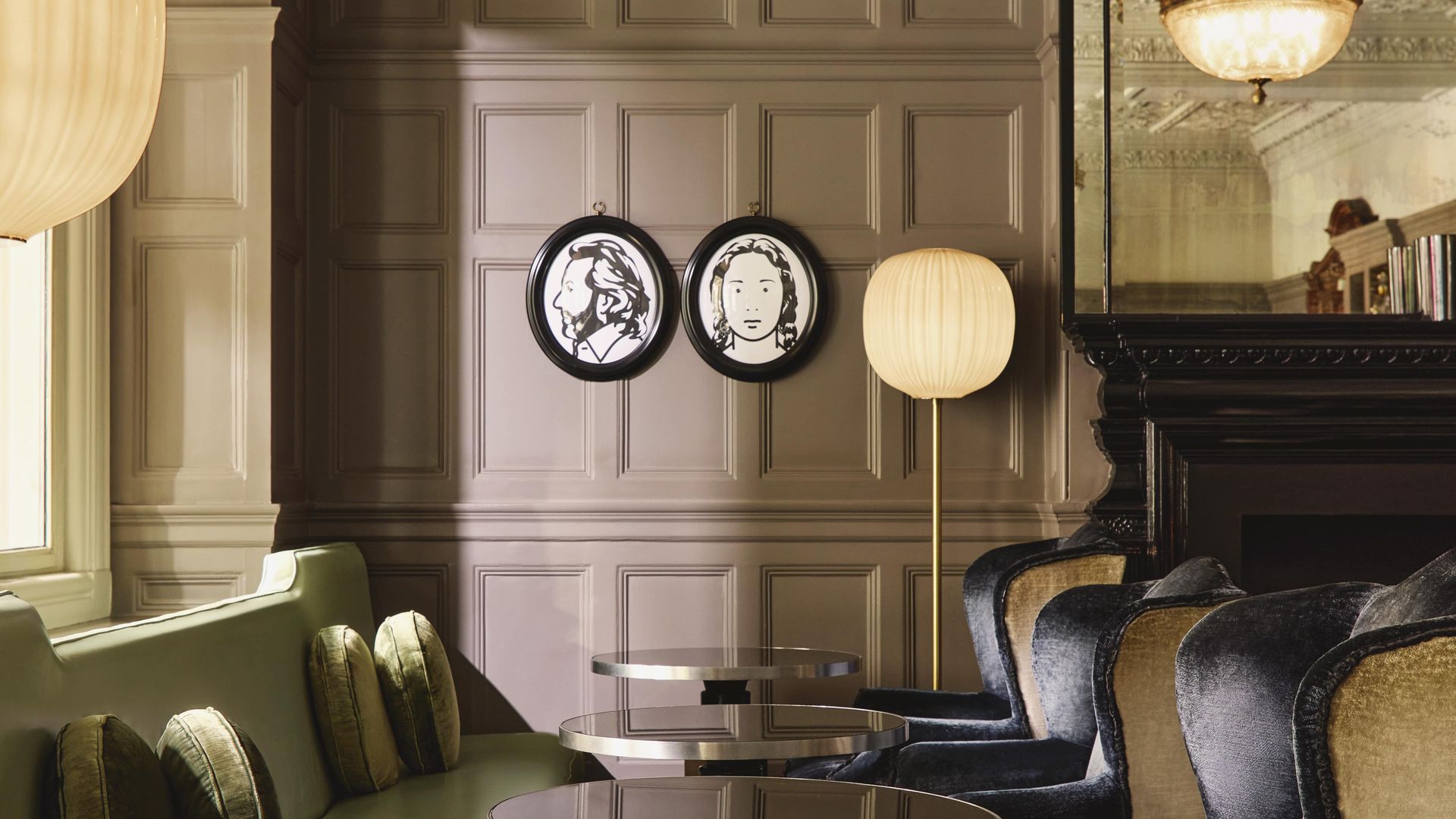 Chic lounge with velvet seating, round tables, and decorative wall portraits in a heritage-style interior.