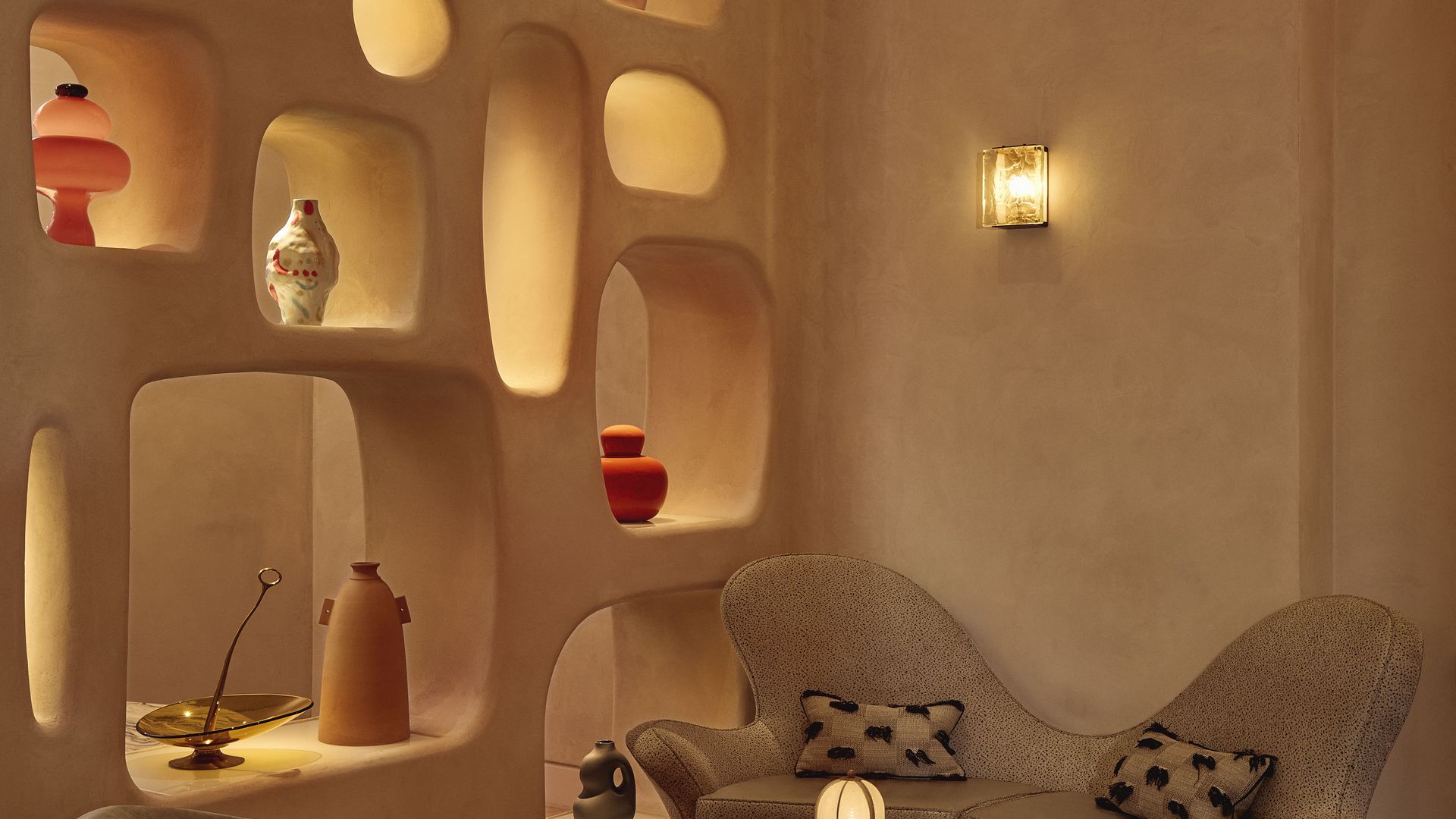 Curved lounge seating with sculptural shelving and warm lighting in a contemporary, artful interior.