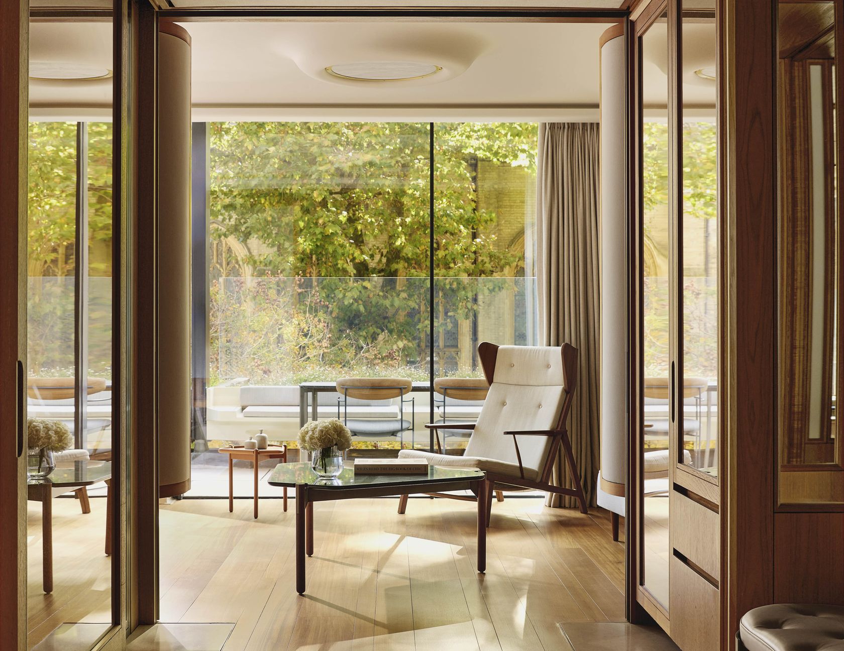 Elegant suite interior with mid-century furnishings and views of a private terrace garden.