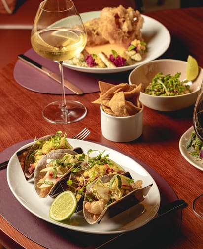 Tranquil indoor pool with stone walls, soft lighting, and curtained poolside cabanas creating a calming retreat