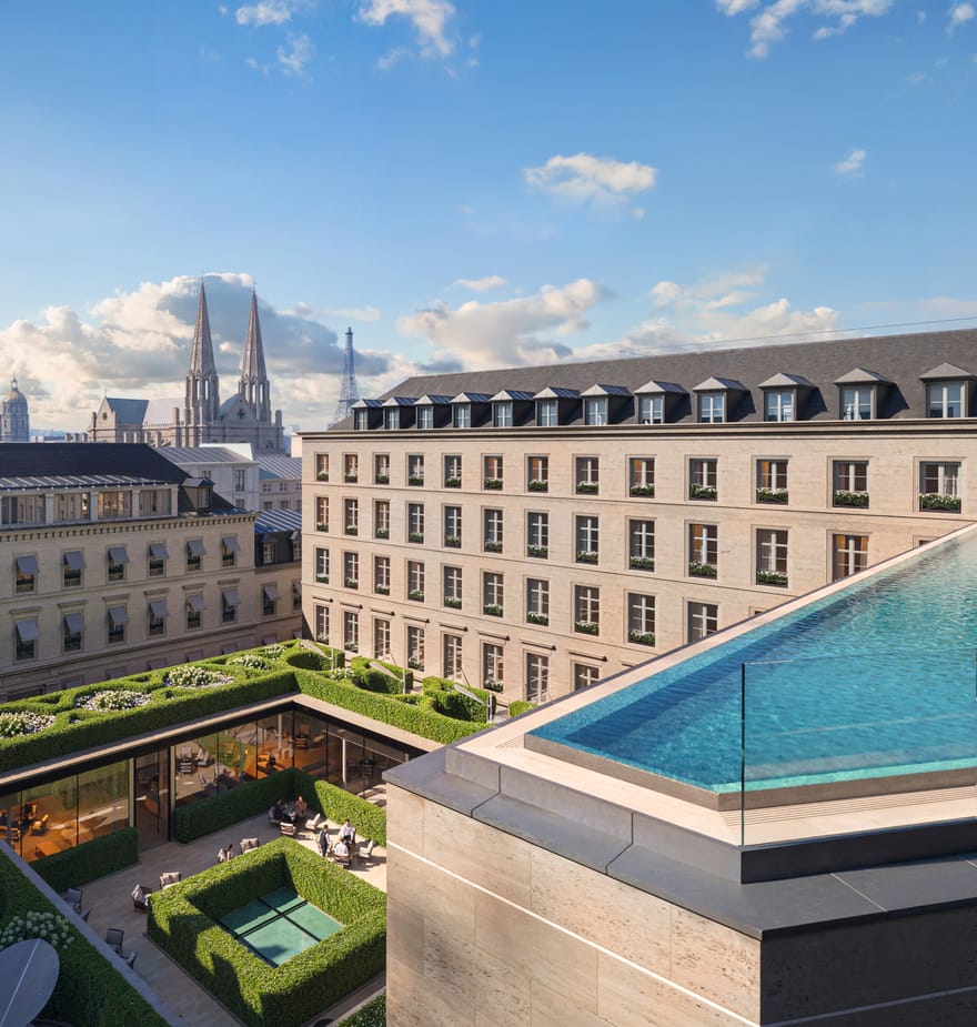 Rooftop infinity pool with sun loungers overlooking Paris rooftops and landmarks including the Eiffel Tower in the background.
