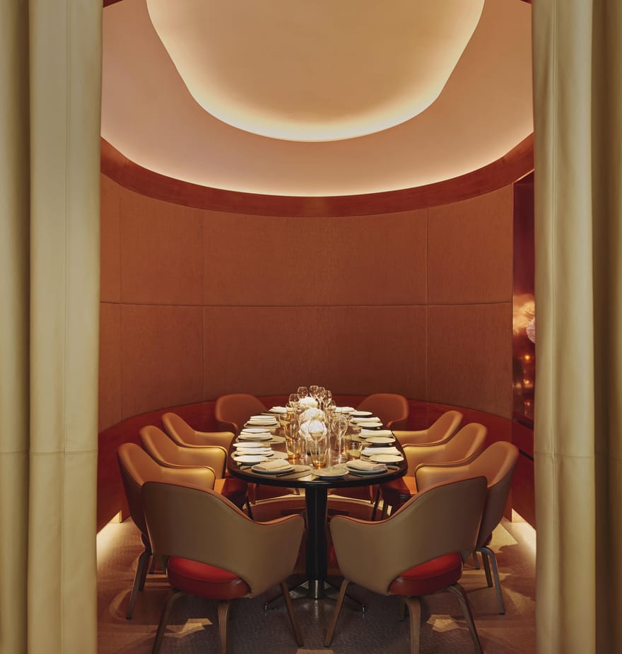 Intimate private dining room with elegant seating, soft lighting, and a warmly lit ceiling, creating a cozy, sophisticated ambiance.