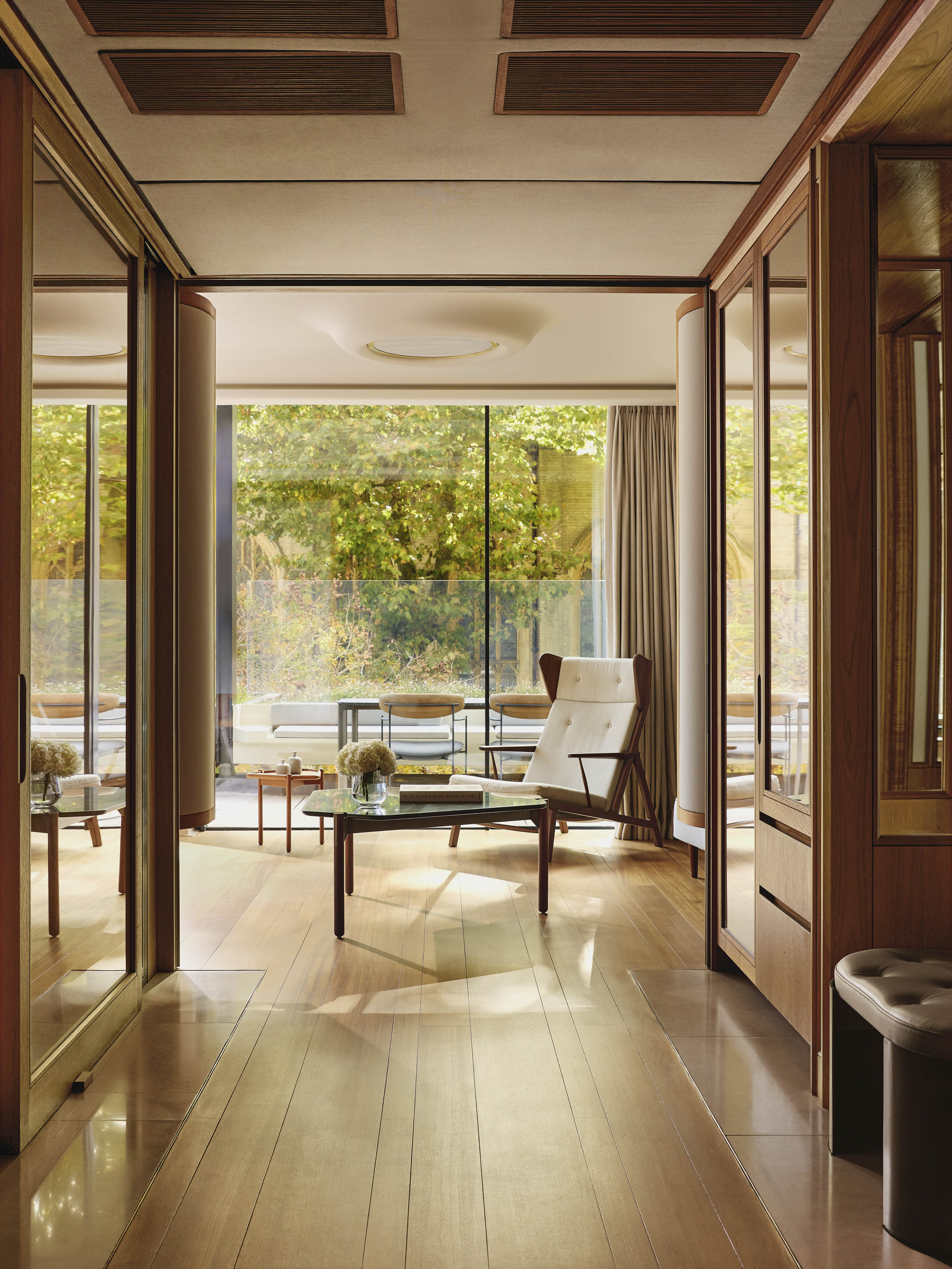 Elegant suite interior with mid-century furnishings and views of a private terrace garden.