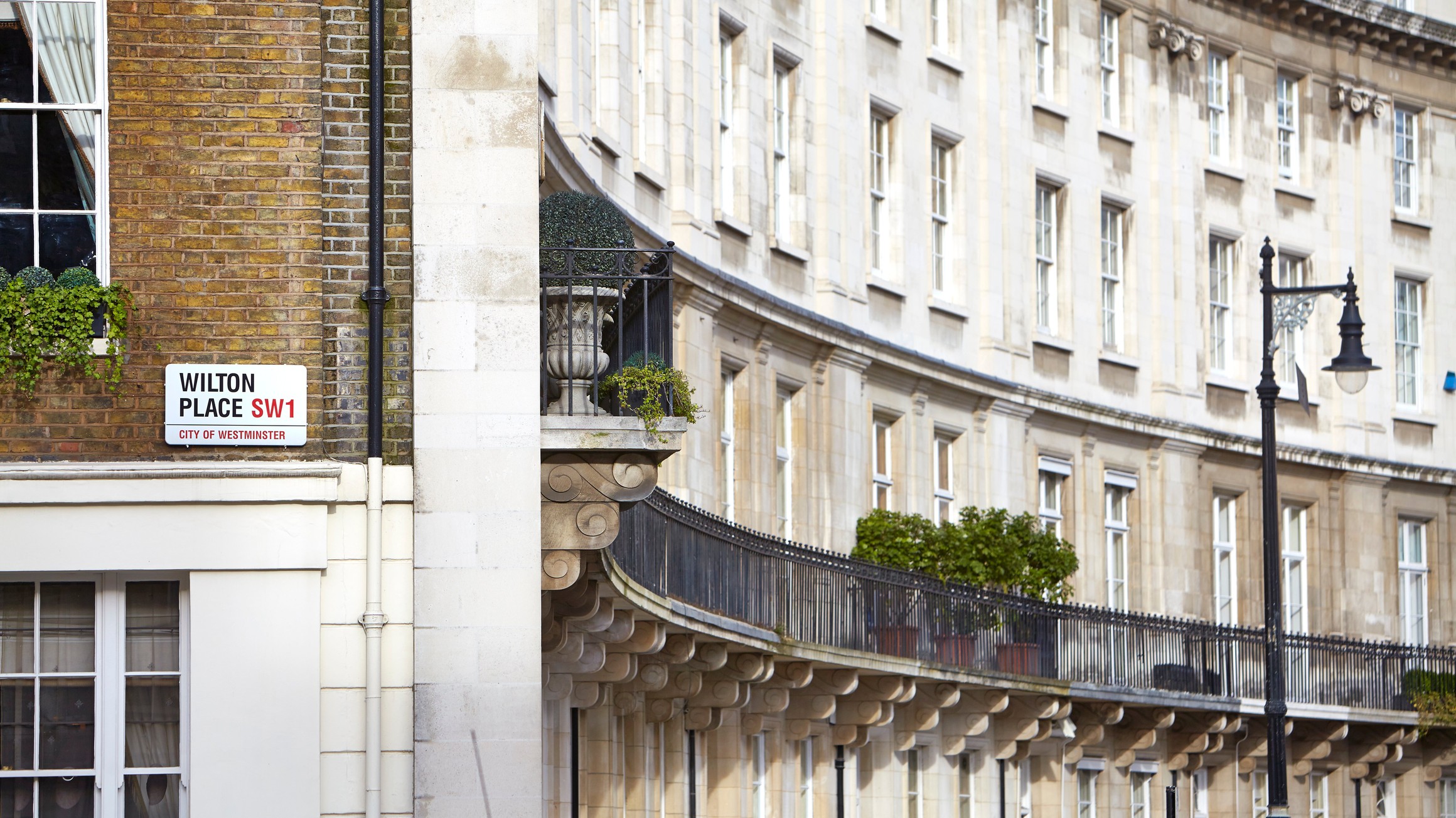 Wilton Place SW1 street sign with elegant Georgian architecture, wrought-iron railings, and classic Westminster charm in the background.