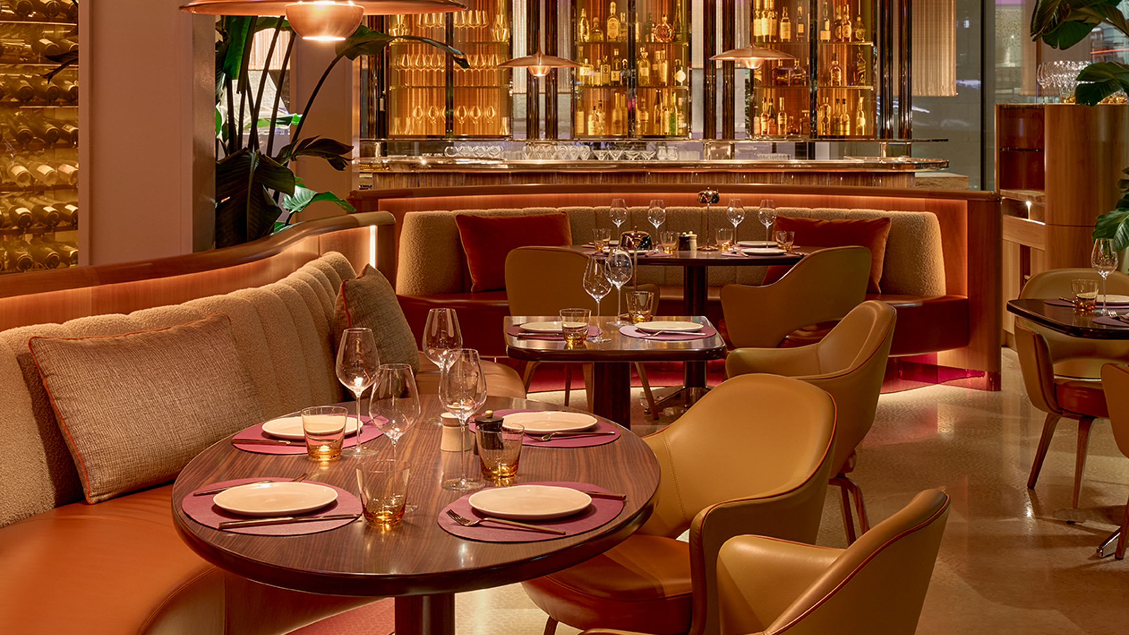Luxurious dining space with warm tones, curved seating, and a luminous bar, exuding elegance and contemporary sophistication.