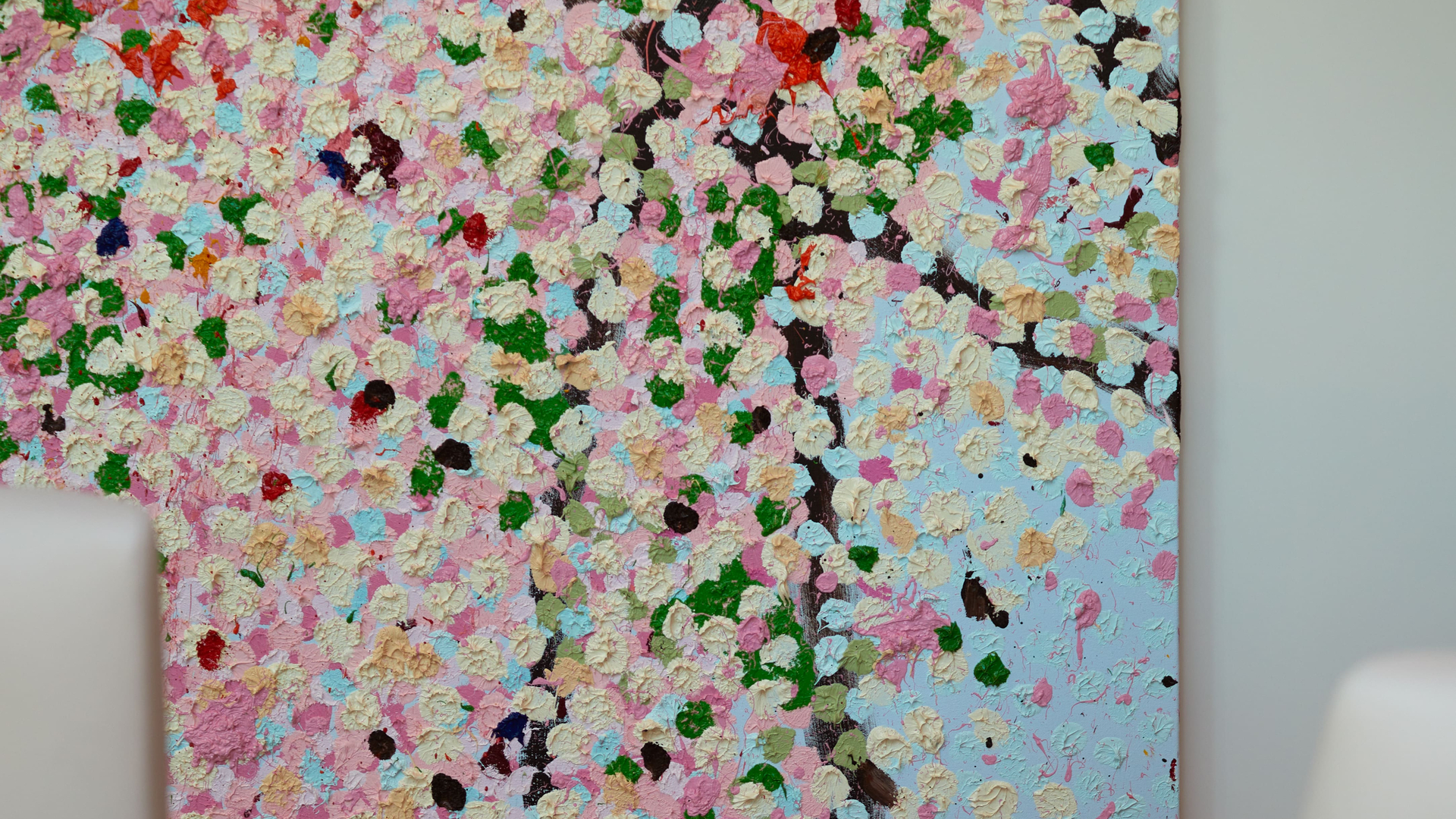 A vibrant floral-inspired abstract painting featuring textured strokes in pastel pinks, greens, and blues, hanging on a white wall.