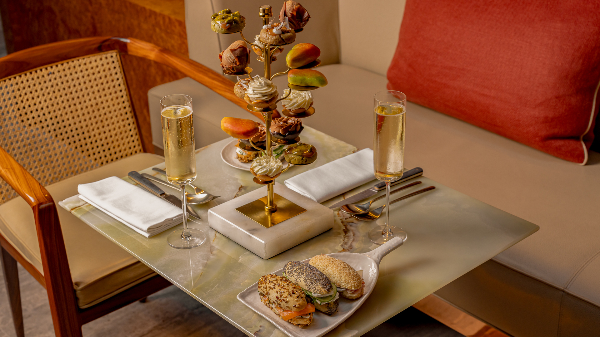 A luxurious table setting at The Berkeley featuring a gold pastry tree with exquisite desserts, savory sandwiches, and glasses of champagne.