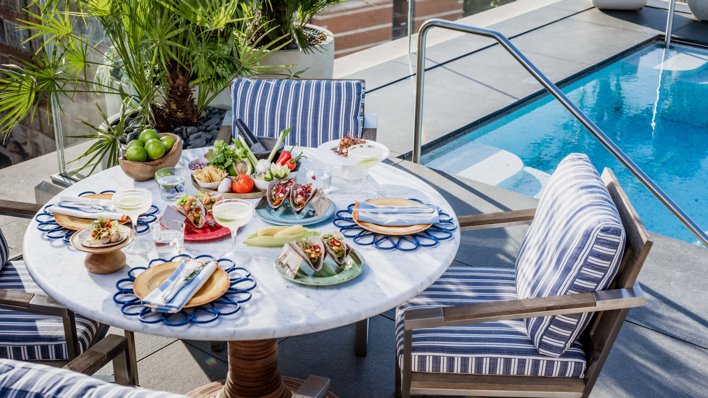 A chic poolside setting with vibrant tacos, fresh ingredients, and striped seating, offering a relaxed yet sophisticated dining experience.