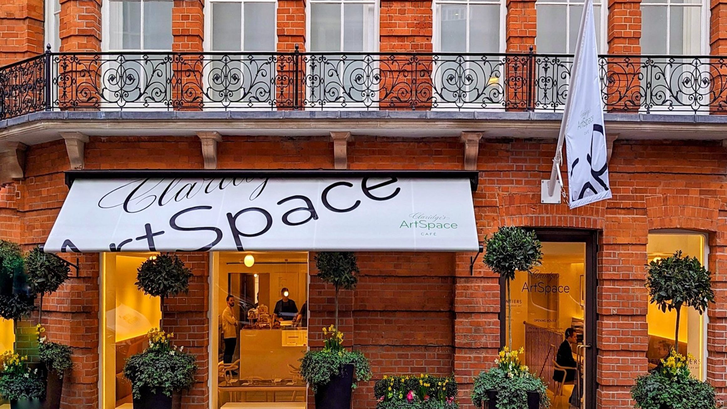 Claridge's ArtSpace exterior showcases vibrant red-brick architecture, elegant awnings, and curated greenery, inviting guests into a creative haven.