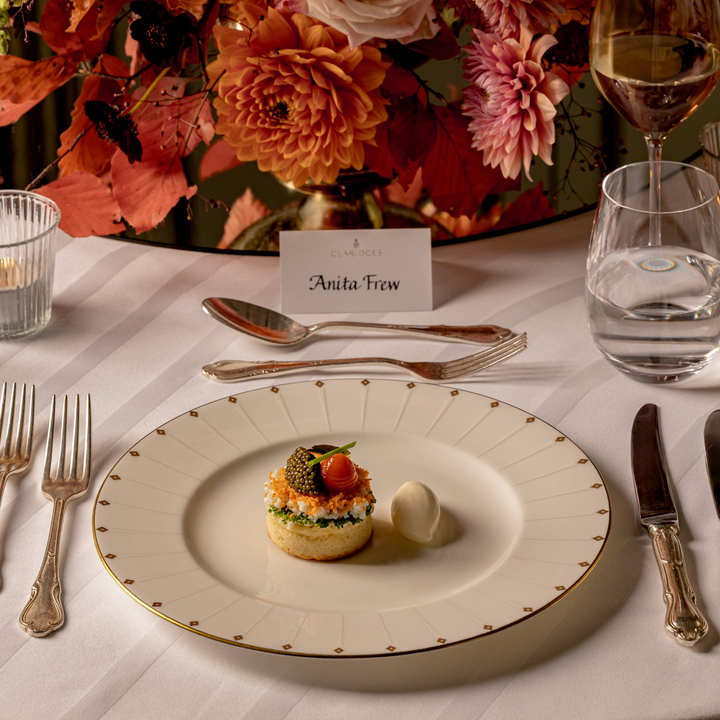 Elegant table setting at Claridge’s, showcasing a gourmet dish with fine cutlery, floral centrepiece, and personalized name card