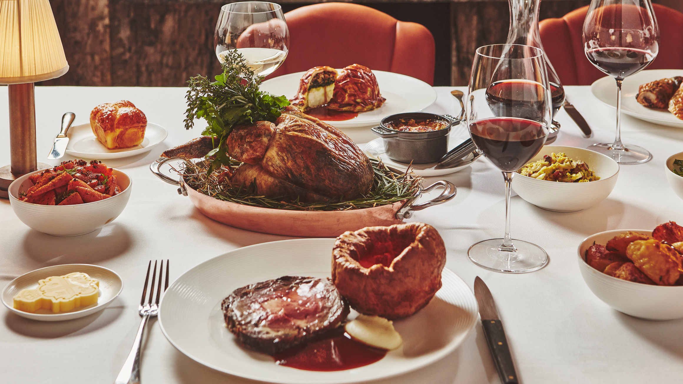 An elegant tablescape featuring roasted chicken, Yorkshire pudding, rich sides, and fine wine, perfect for a luxurious feast.
