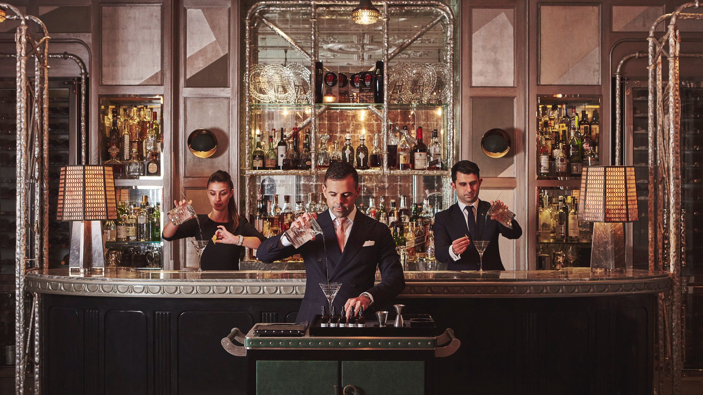 Artisan mixologists craft bespoke cocktails in an opulent bar setting, blending tradition with contemporary sophistication.