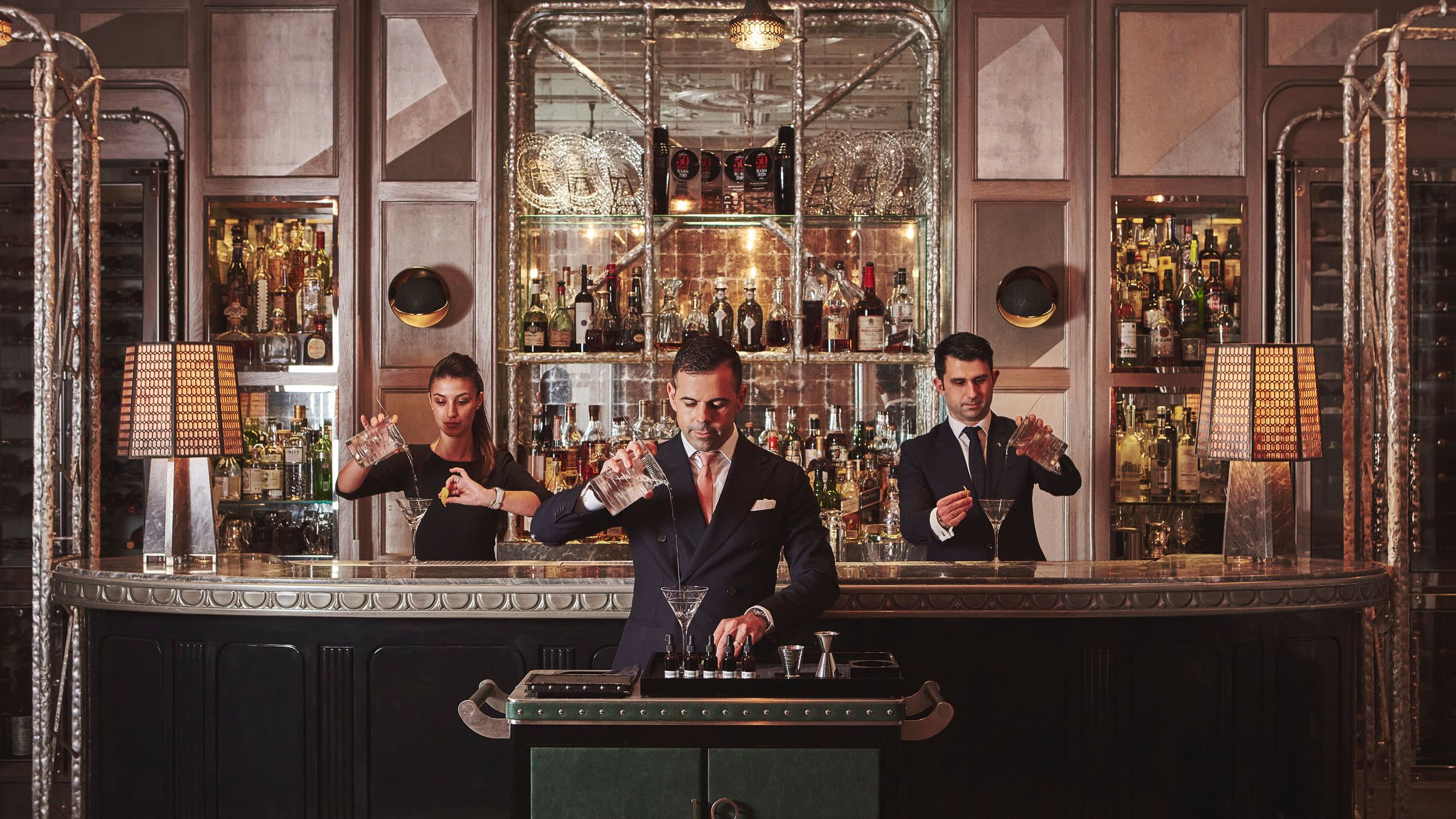 Artisan mixologists craft bespoke cocktails in an opulent bar setting, blending tradition with contemporary sophistication.