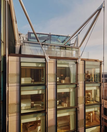 The Emory's modern facade showcases floor-to-ceiling windows, reflecting bespoke interiors and architectural harmony under its striking steel frame.