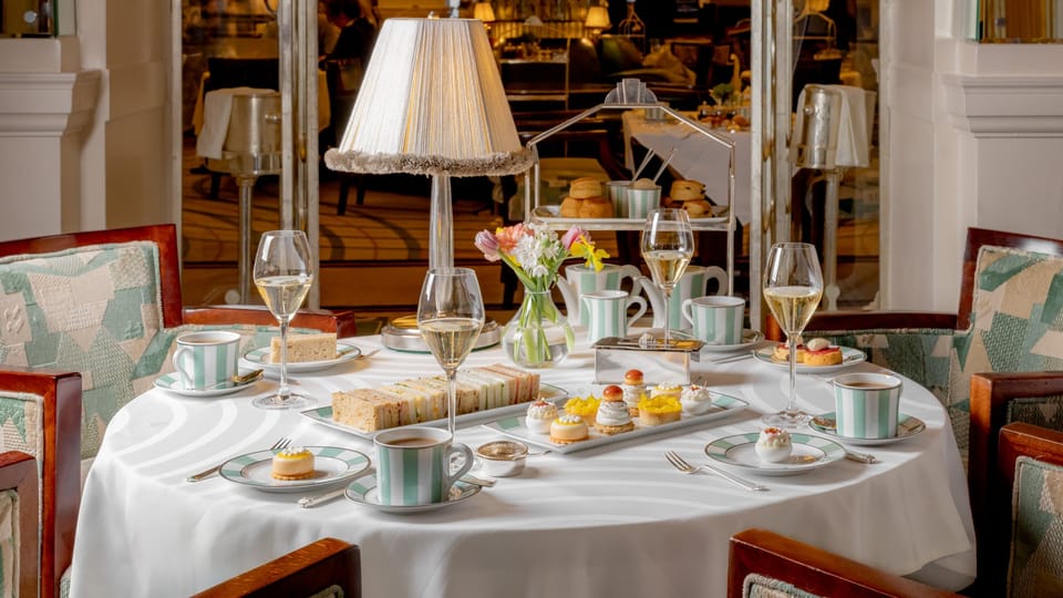 An elegant afternoon tea setting with fine china, delicate pastries, finger sandwiches, and champagne, exuding timeless sophistication and charm.