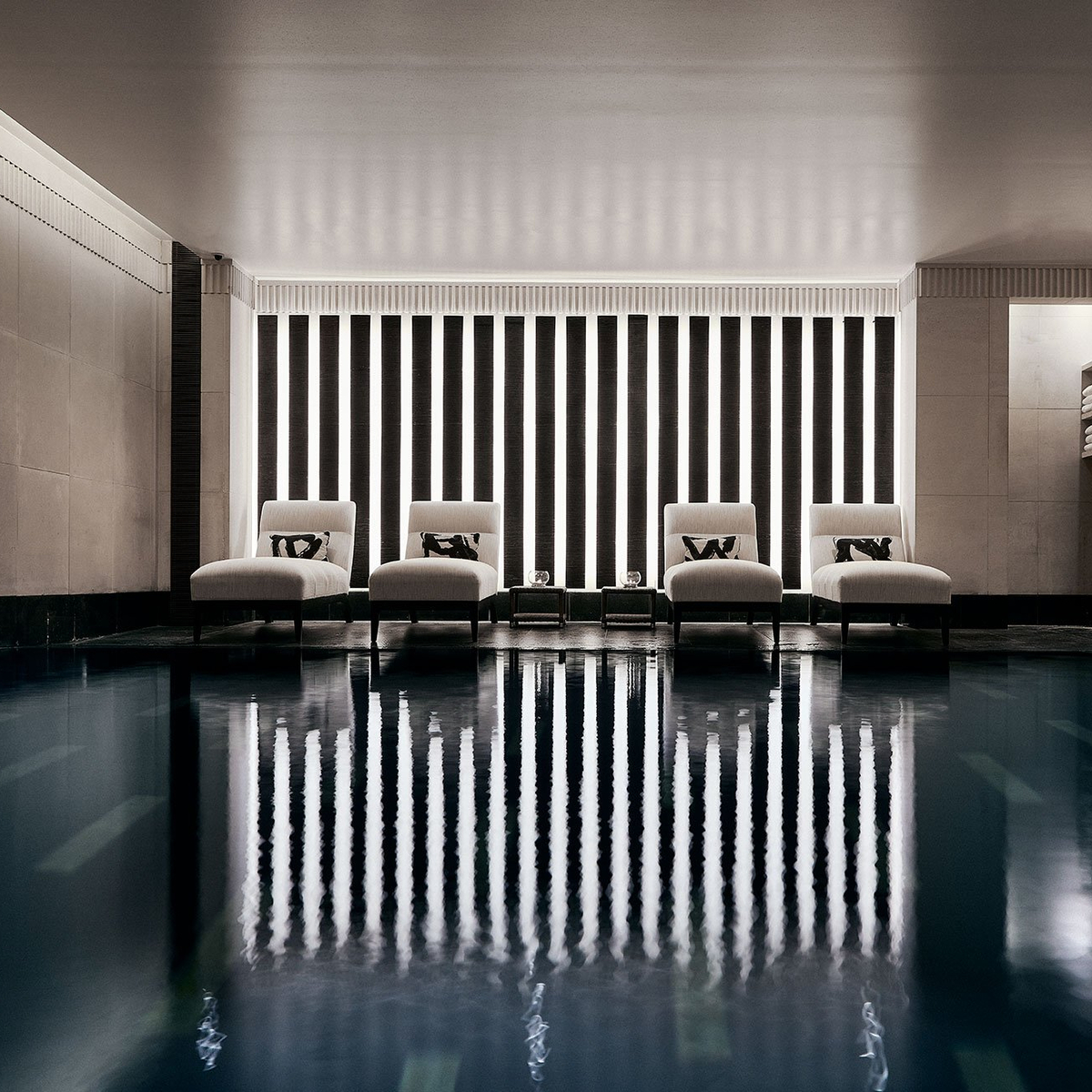 A serene indoor pool retreat with minimalist design, plush loungers, and ambient lighting, offering pure relaxation and tranquility.
