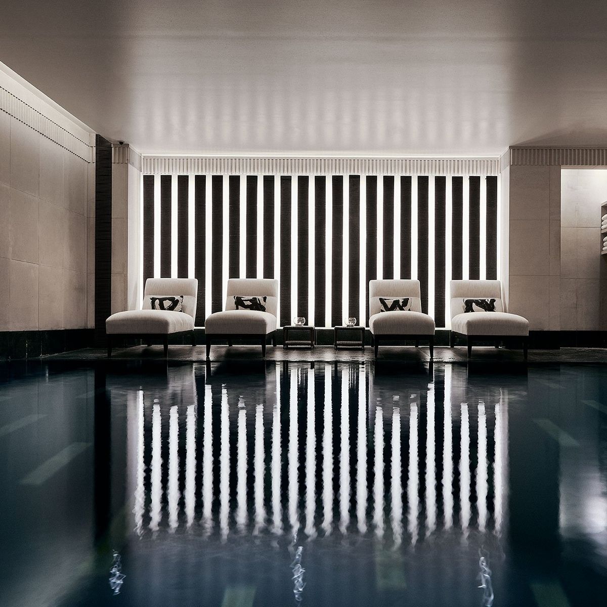 A serene indoor pool retreat with minimalist design, plush loungers, and ambient lighting, offering pure relaxation and tranquility.