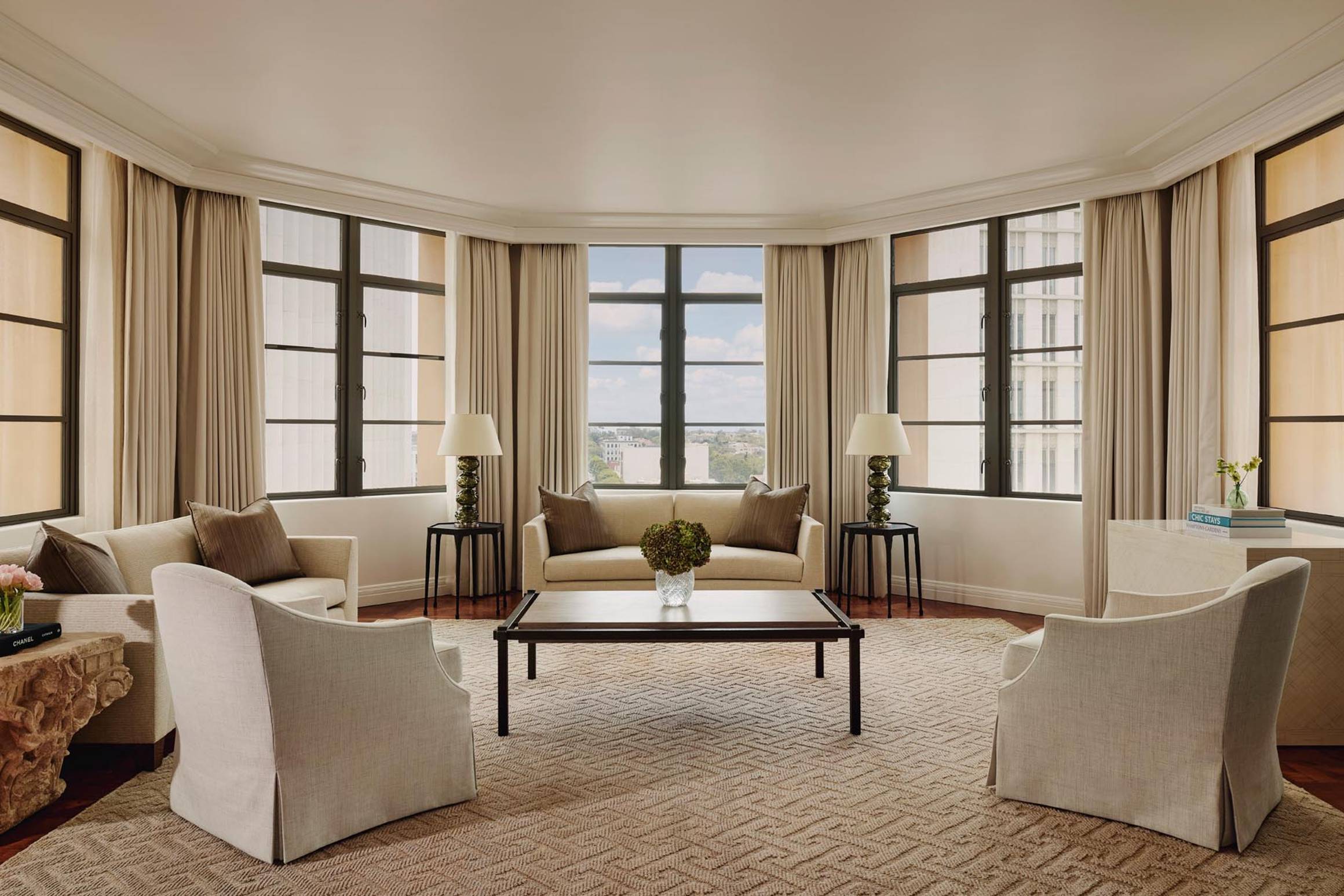 A sunlit sitting area with plush seating, panoramic windows, and warm neutral tones for a serene ambiance