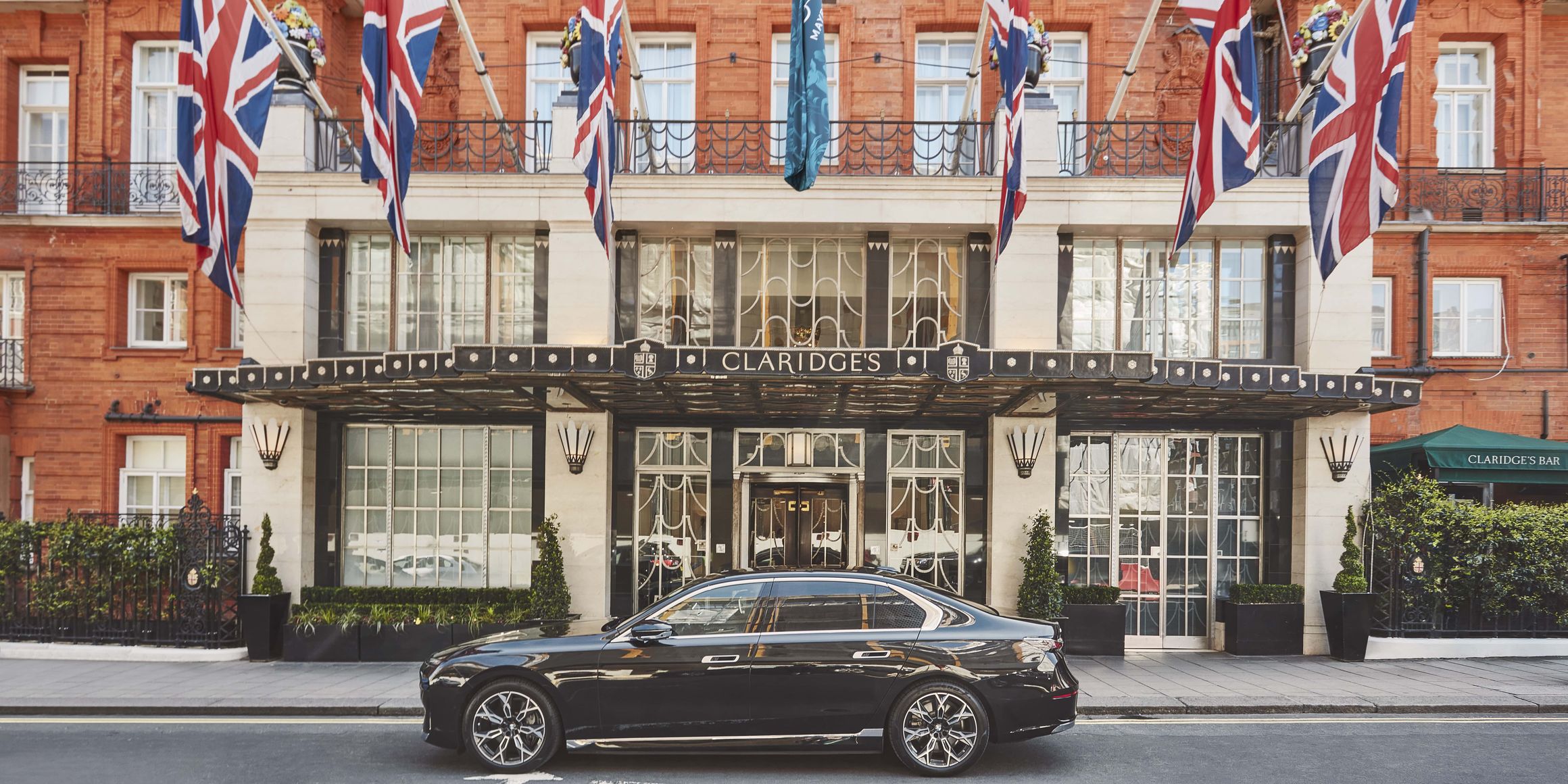 The grand entrance of Claridge's, adorned with Union Jack flags and a sleek black car parked outside.
