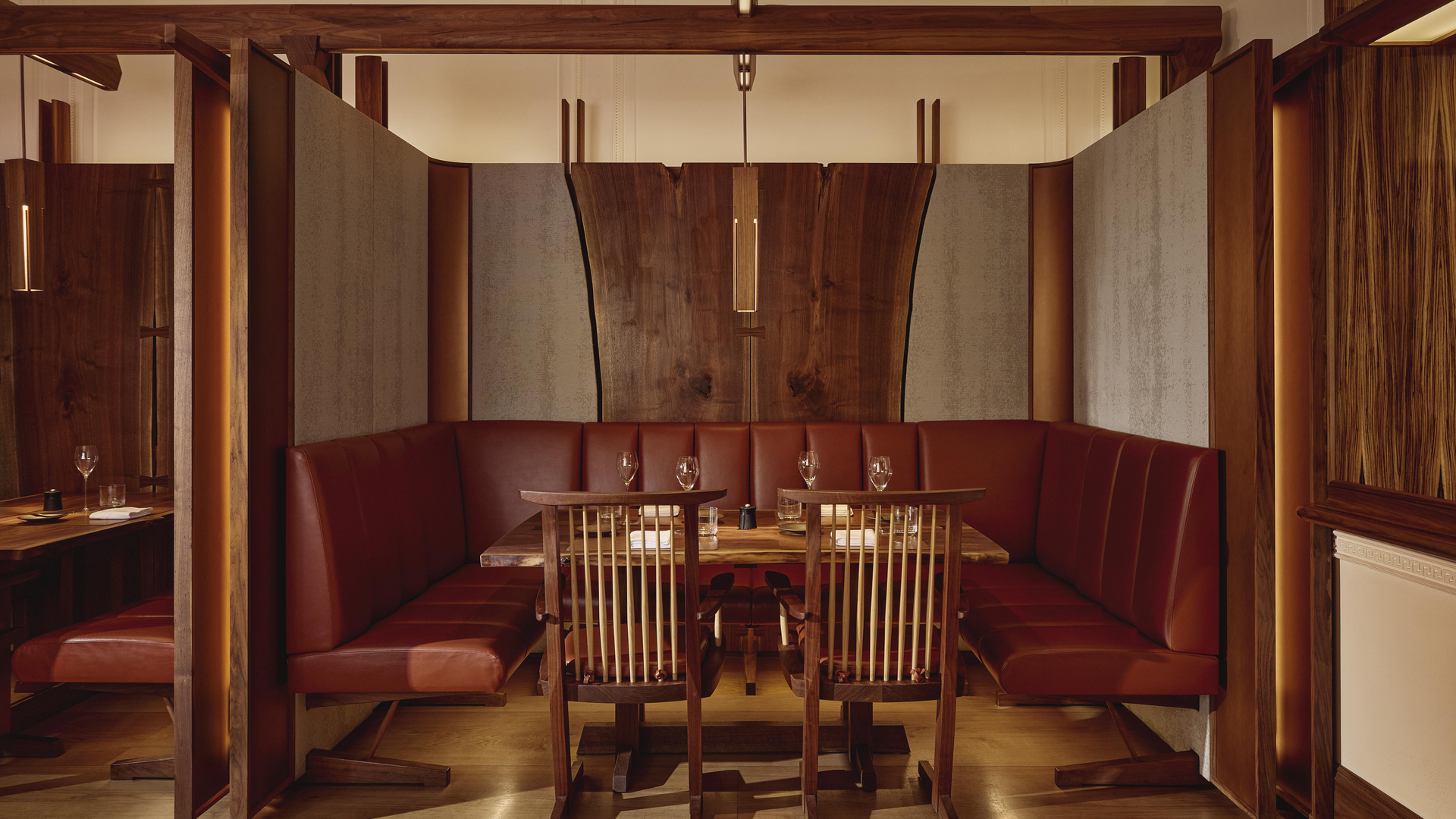 Intimate dining alcove at The Connaught Grill featuring deep red leather banquettes, dark wood finishes, and ambient lighting that accentuates the artisanal craftsmanship of the space.