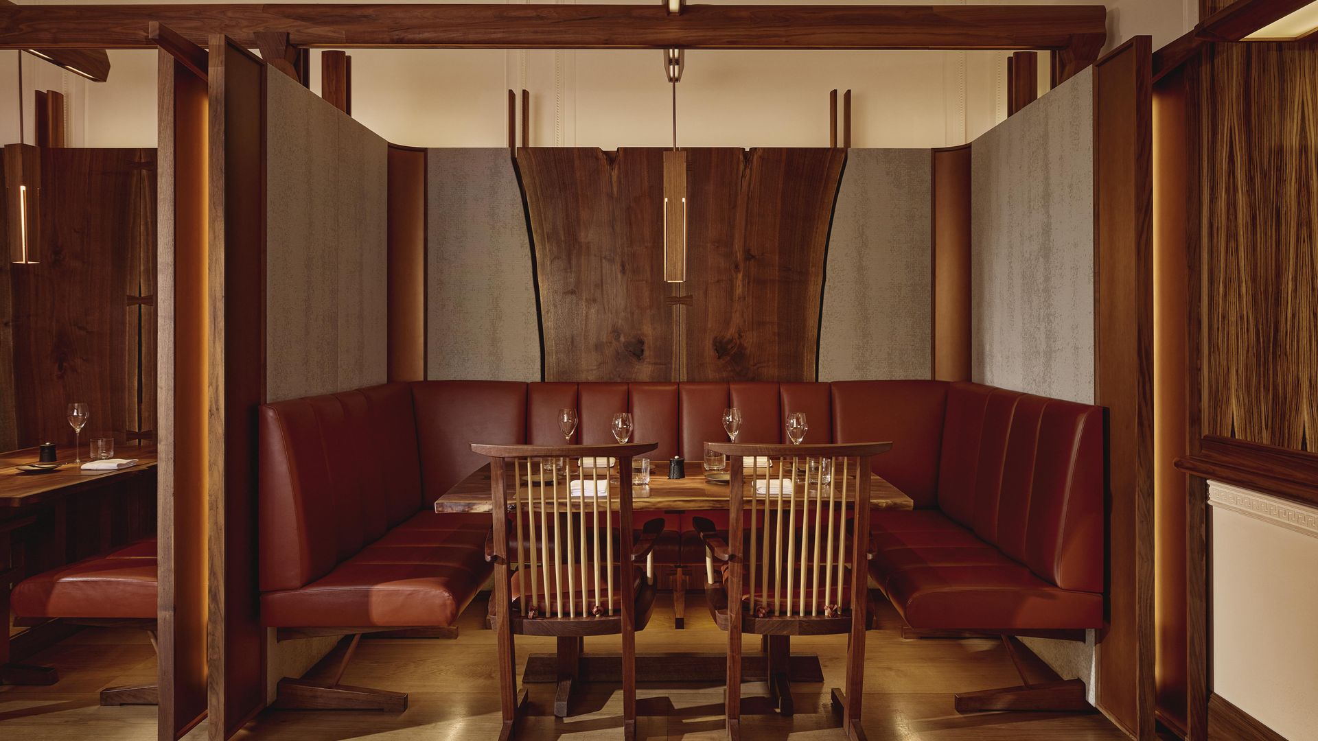 Intimate dining alcove at The Connaught Grill featuring deep red leather banquettes, dark wood finishes, and ambient lighting that accentuates the artisanal craftsmanship of the space.