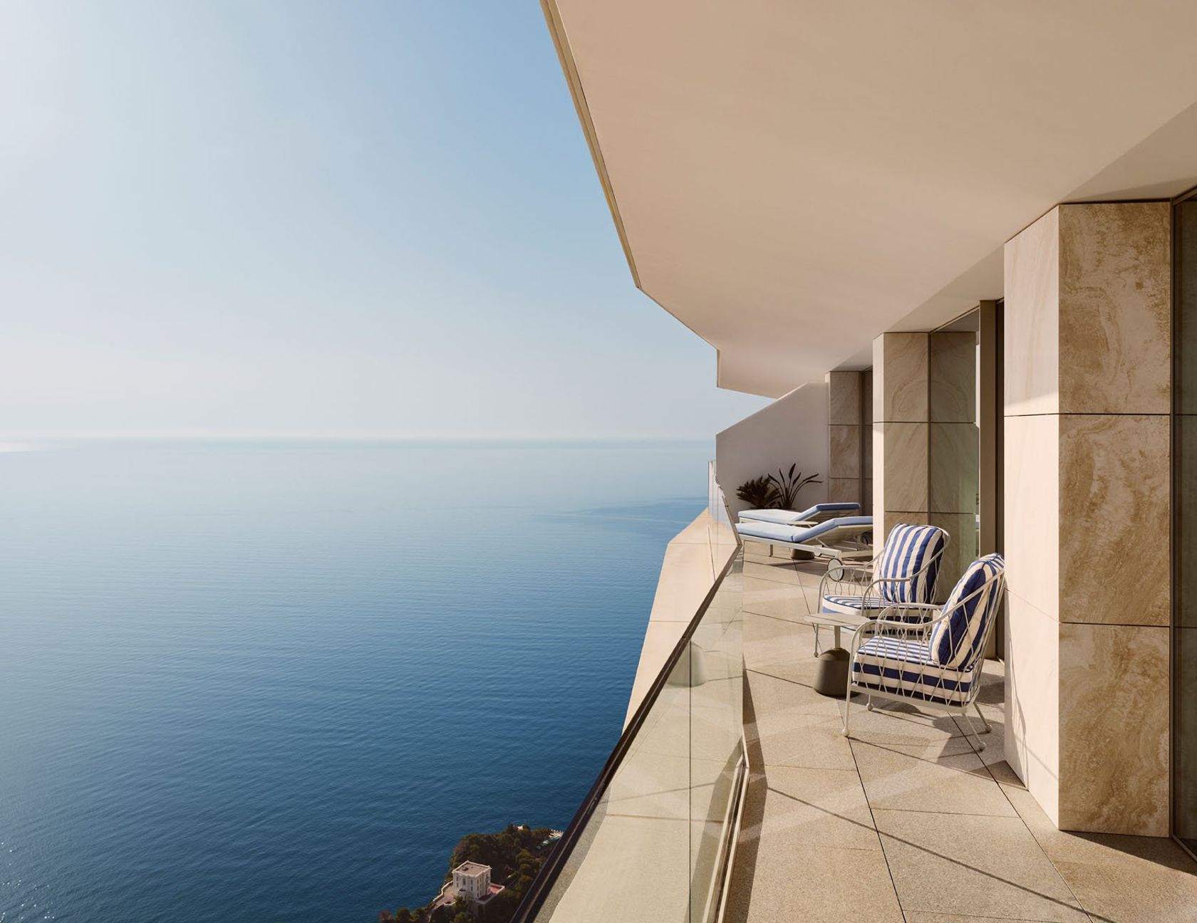 Private balcony with striped lounge chairs, sunbeds, and panoramic sea view, bordered by glass balustrade and stone walls.