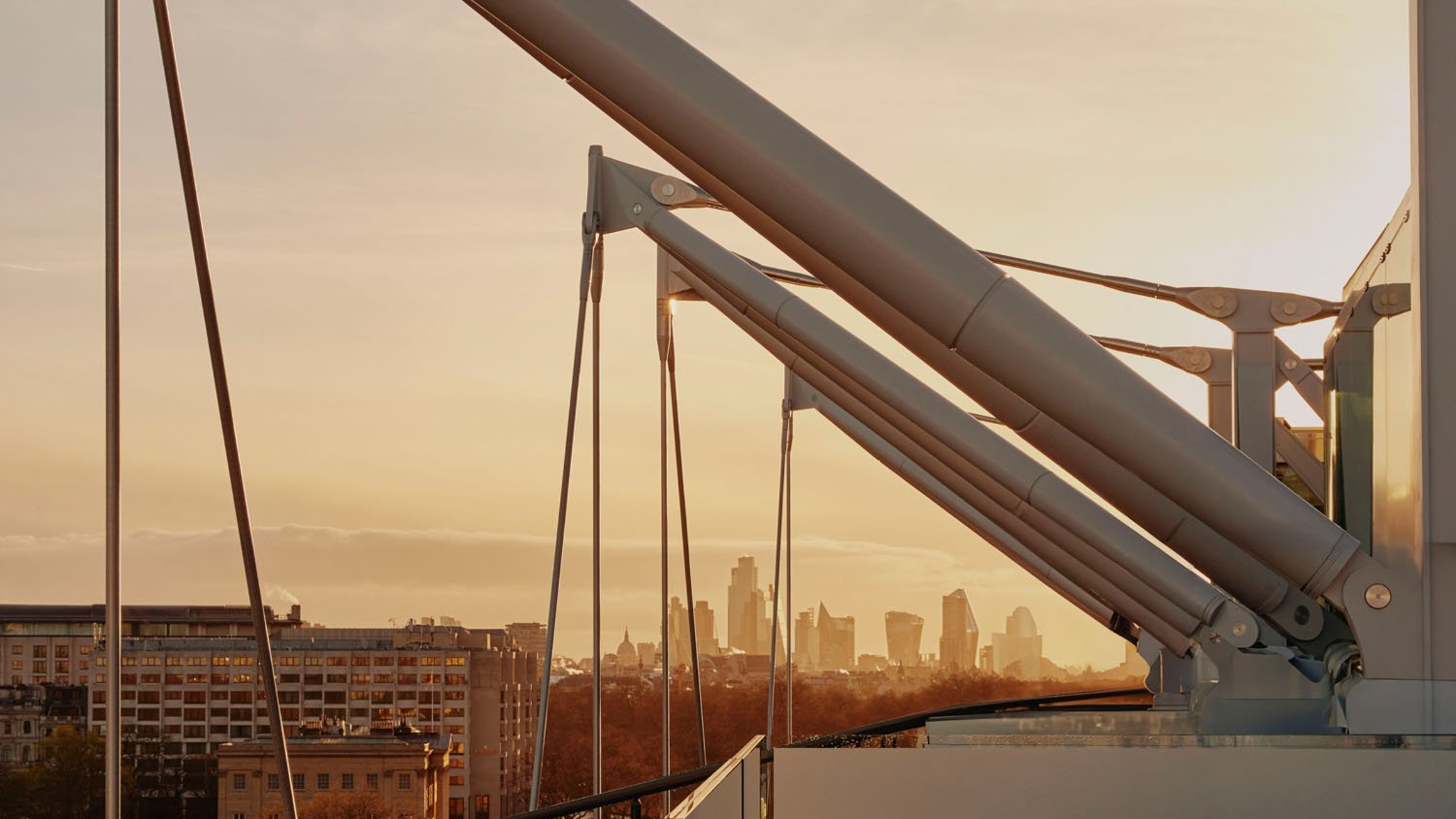 The Emory's striking steel masts frame a golden sunset, overlooking London's skyline and blending engineering precision with architectural elegance.