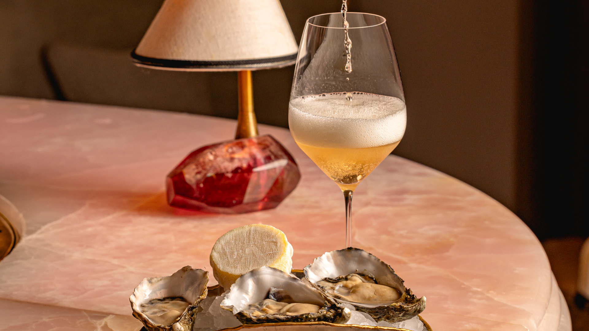 Chilled oysters served with a glass of champagne being poured, exuding effortless indulgence and sophistication.