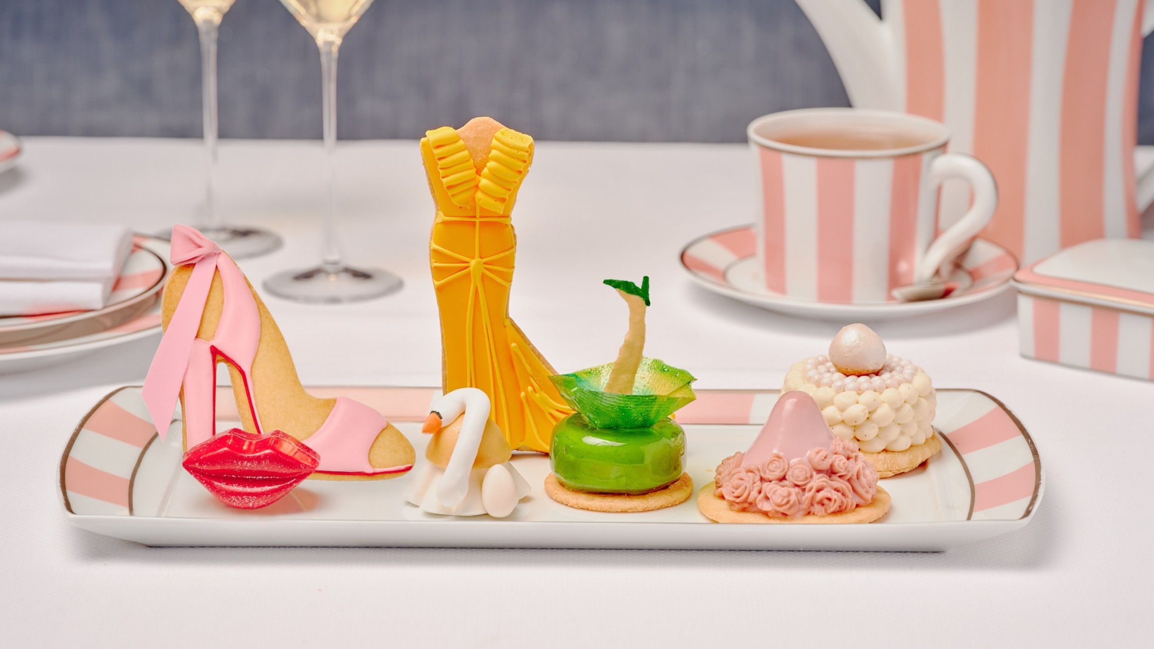 Fashion-themed pastries inspired by red carpet looks, served with champagne and tea on pink-striped china at The Maybourne Beverly Hills